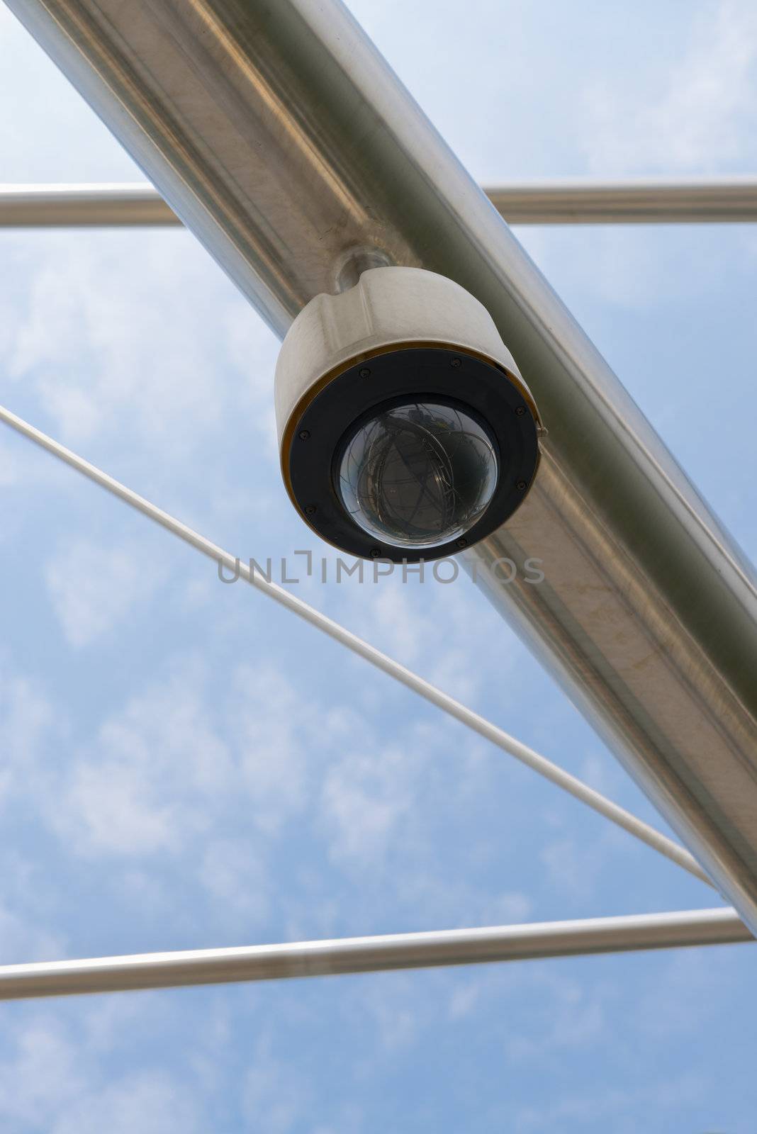 High tech overhead security camera with a blue sky. 
