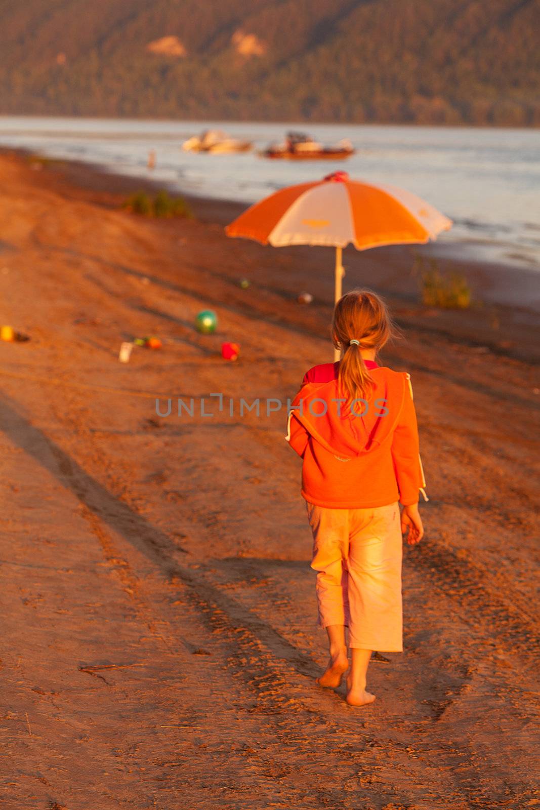 little girl running along the beach in the sunshine by jannyjus