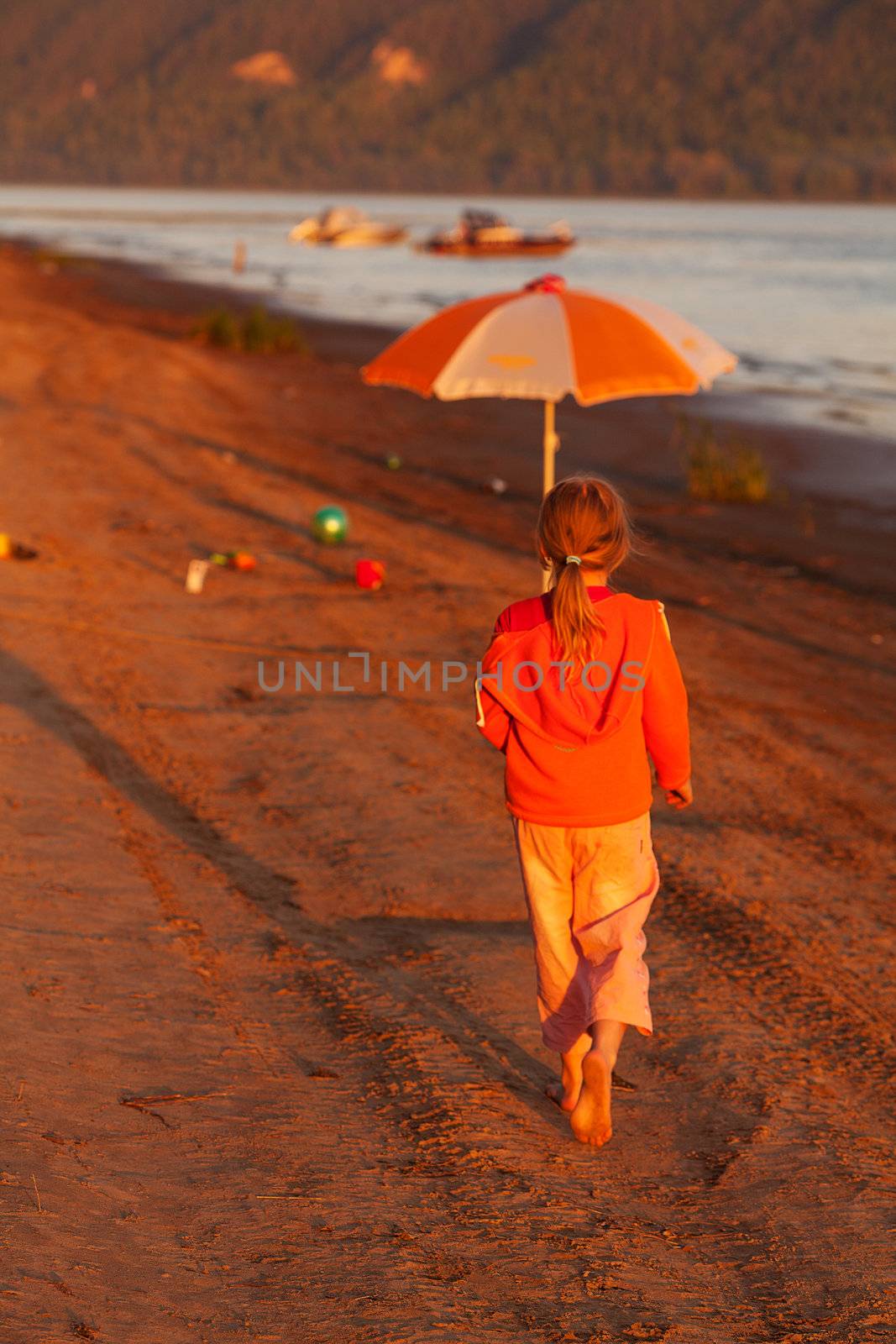 little girl running along the beach in the sunshine by jannyjus