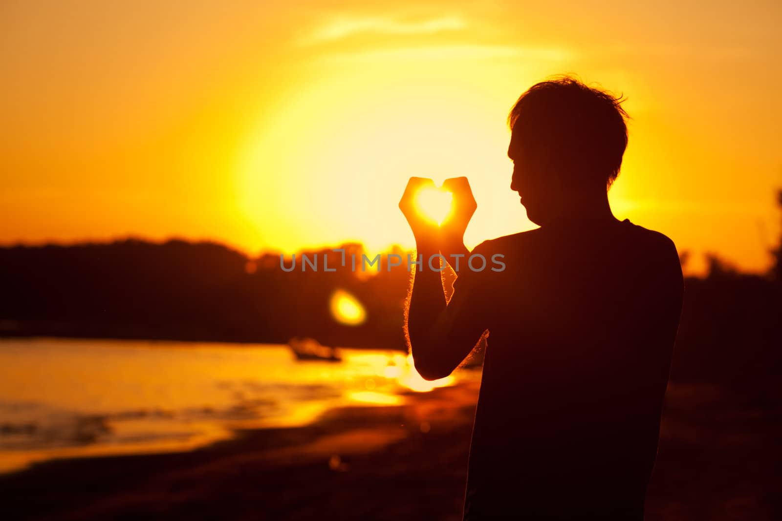young man holding in hands the setting sun