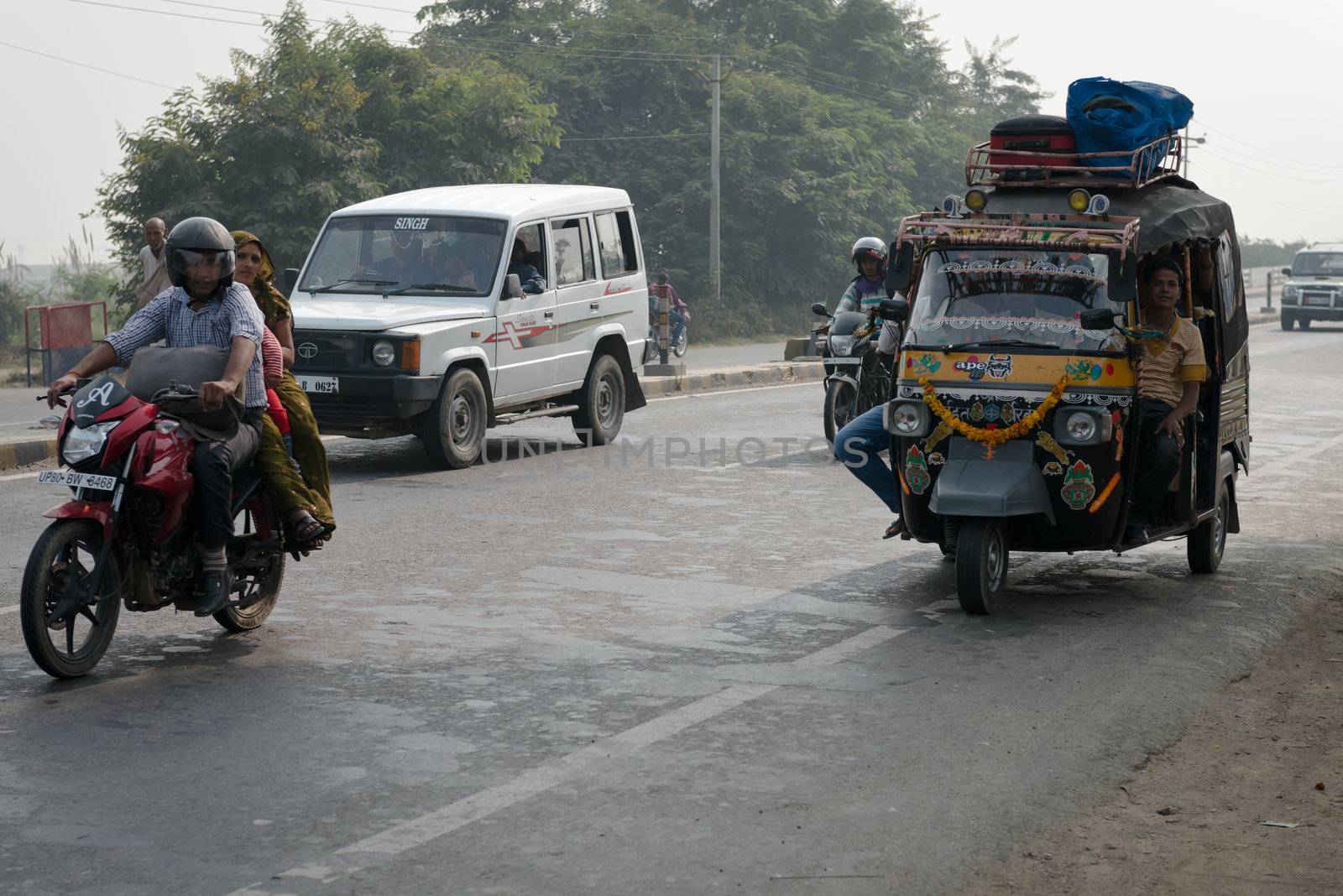 Overloaded motorcycles and tuk-tuks on covered by haze route, Ce by iryna_rasko