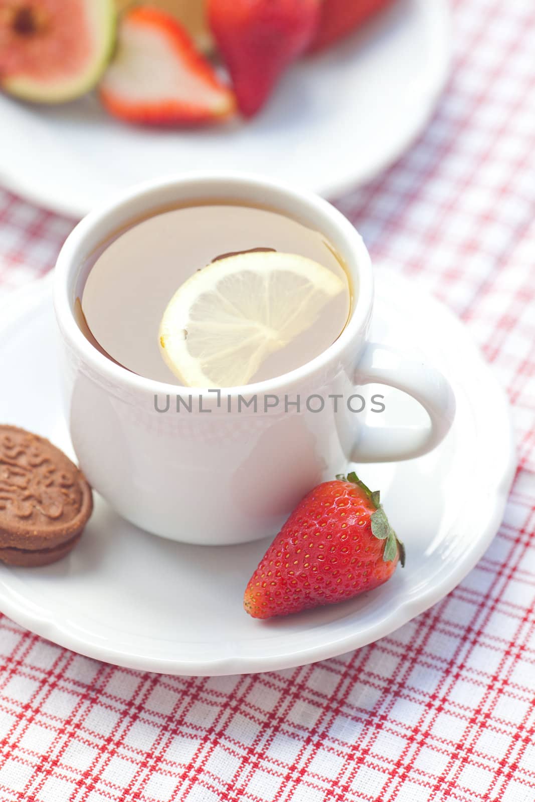 cup of tea,cookie, fig and strawberries on a plate