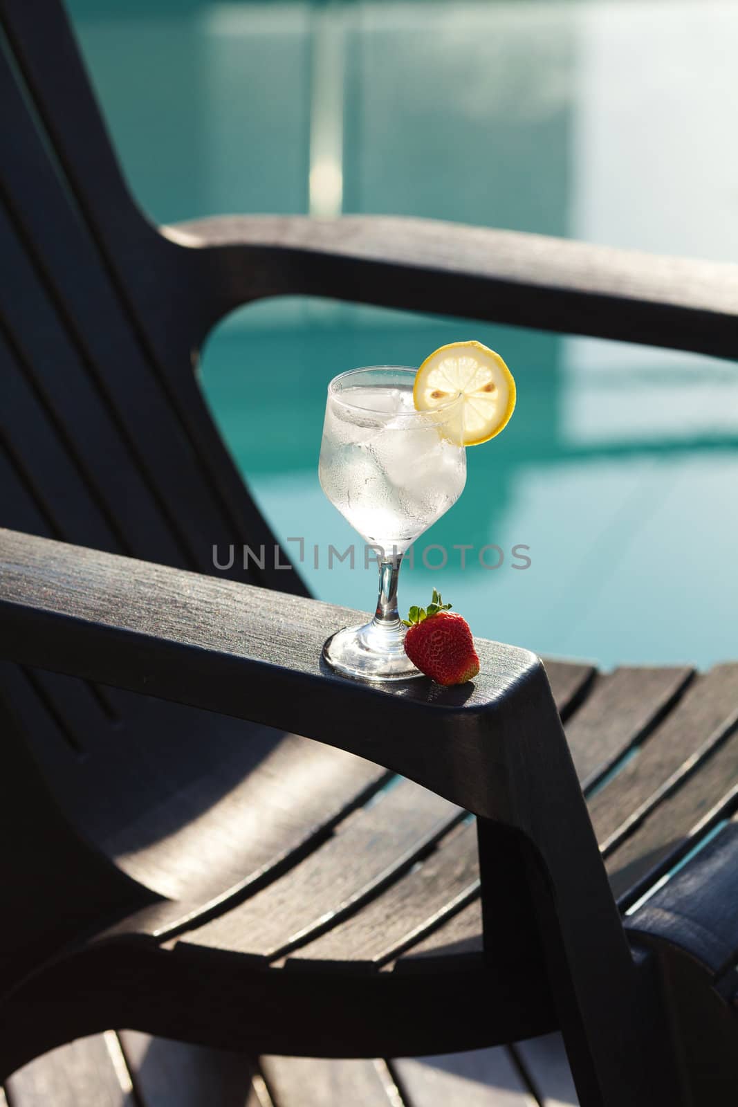 Swimming pool, lounge, a wine glass with ice, lemon and strawberry