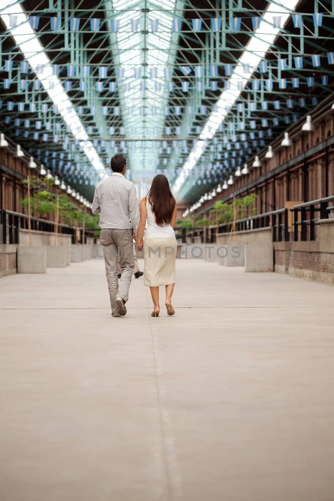 Rear view of couple walking holding hands