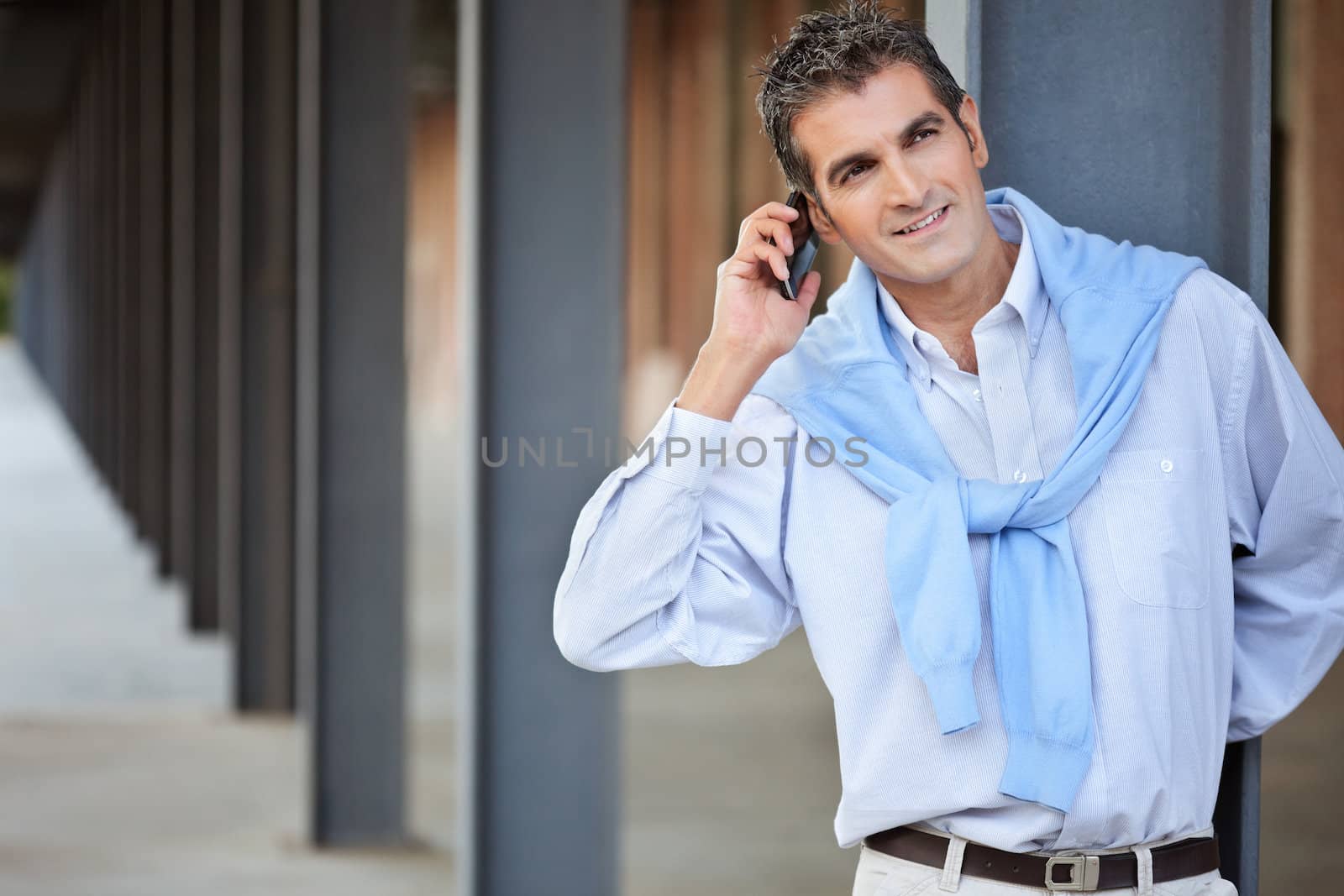 Casual smart man talking on the phone by leaf