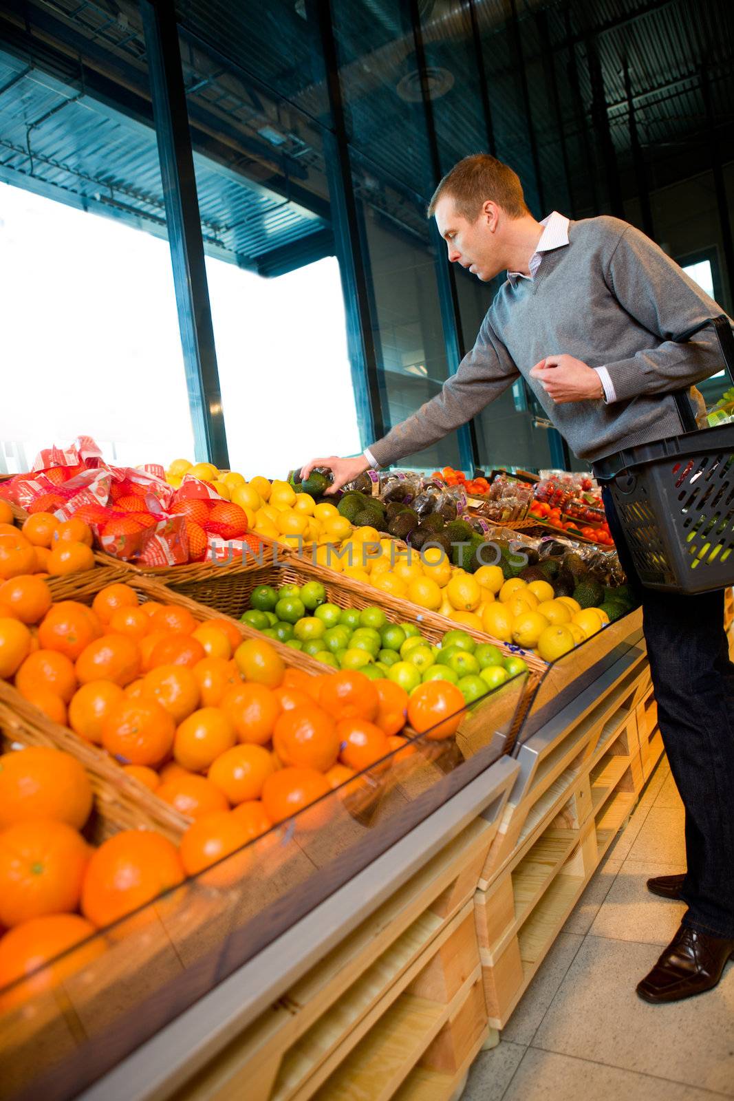 A man in a grocery store buying fruits and vegetables