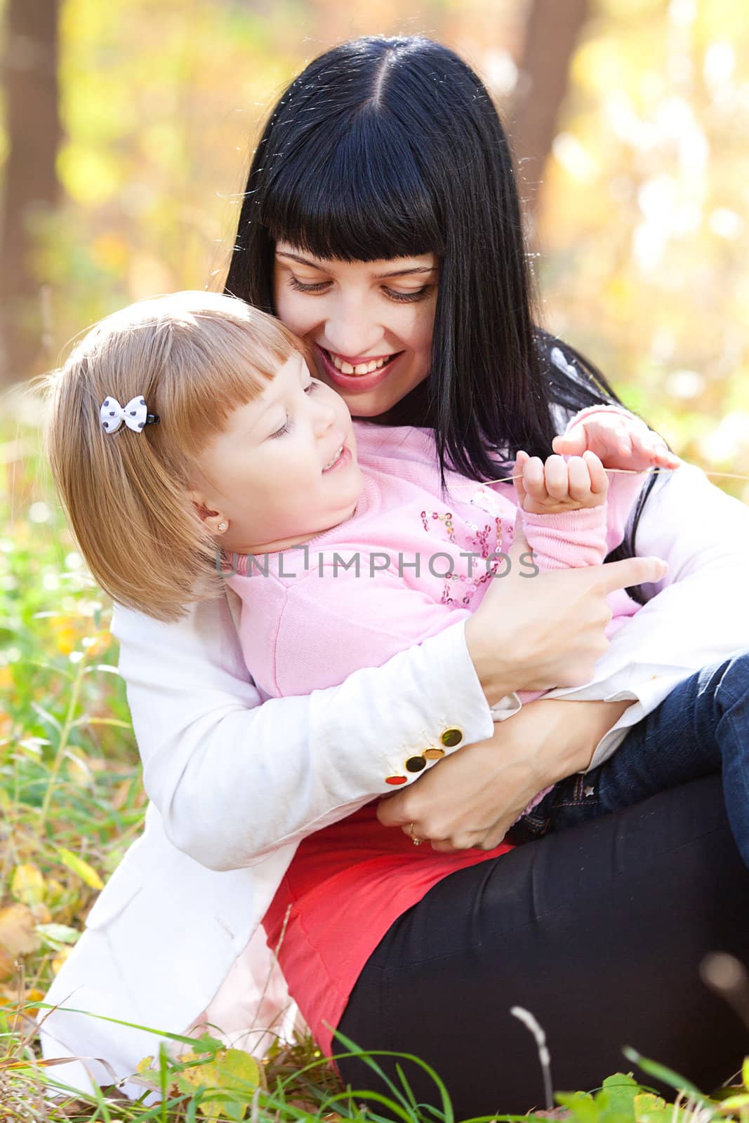 beautiful young mother kissing her daughter in autumn forest by jannyjus