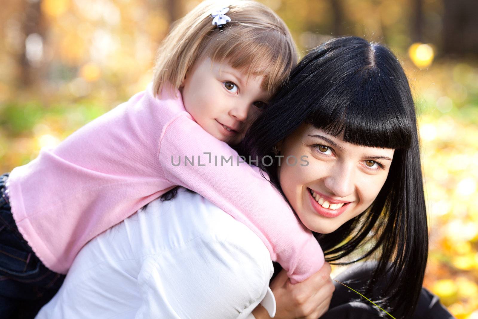beautiful young mother holding her daughter on back by jannyjus