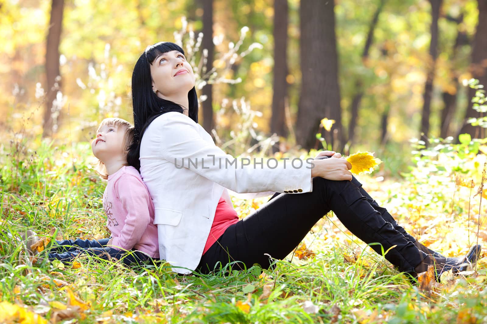 beautiful young mother and her daughter looking up in the autumn forest