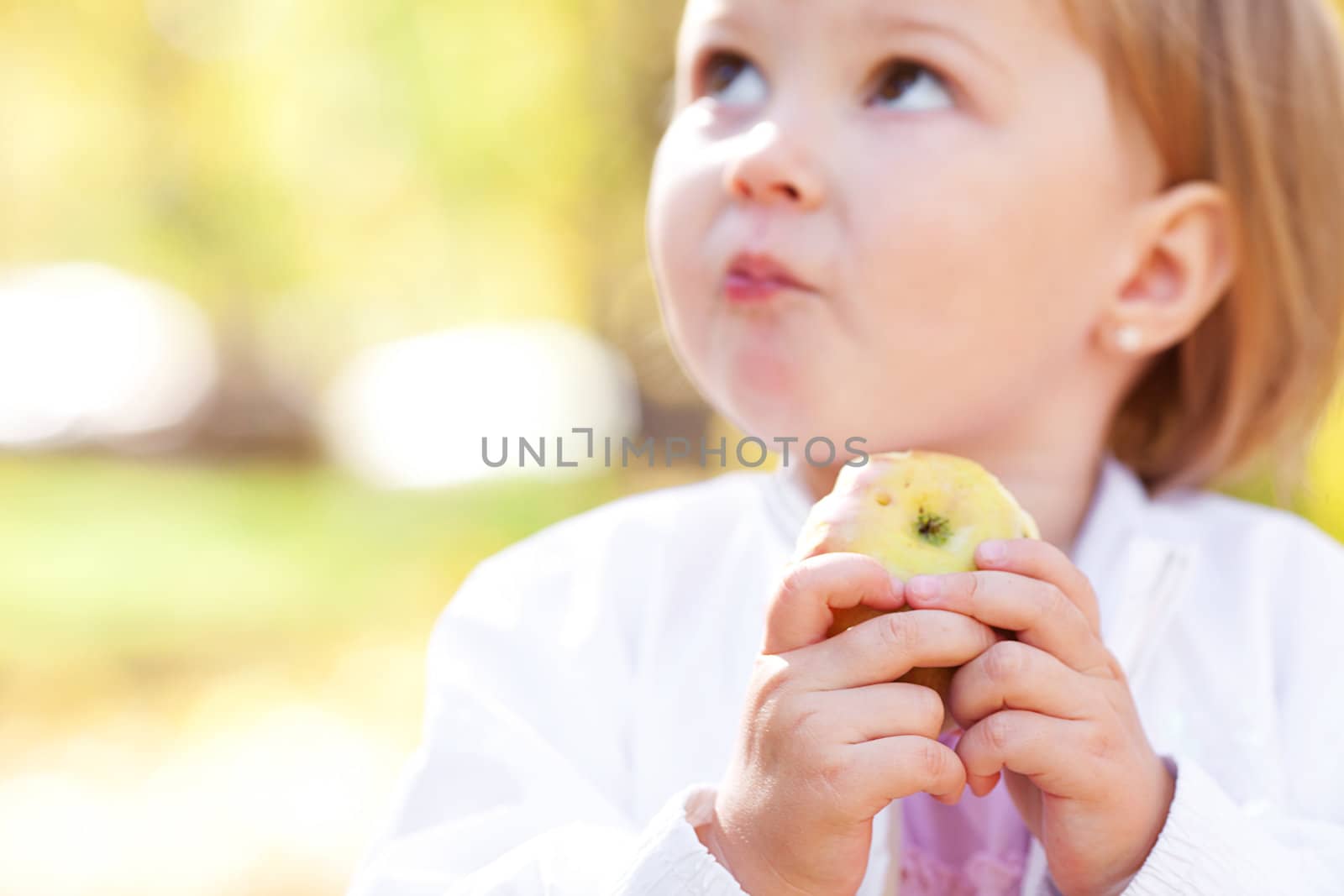 beautiful little girl eating apple in the autumn forest by jannyjus
