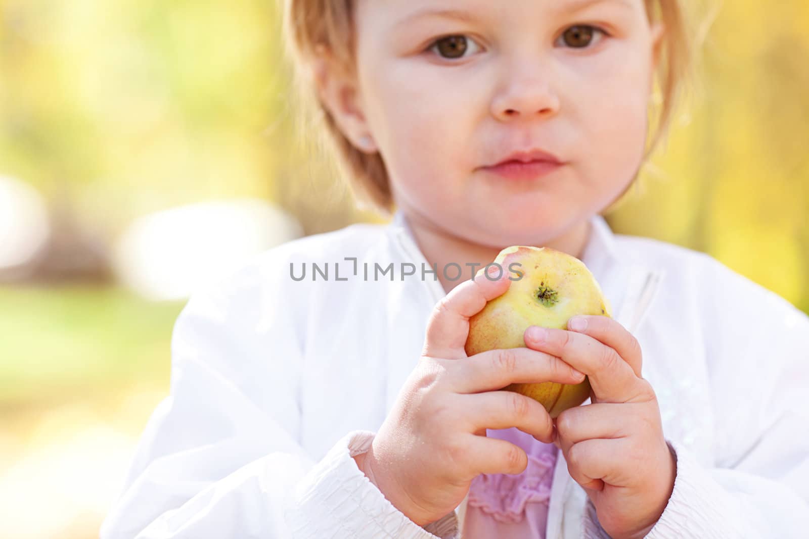 beautiful little girl eating apple in the autumn forest