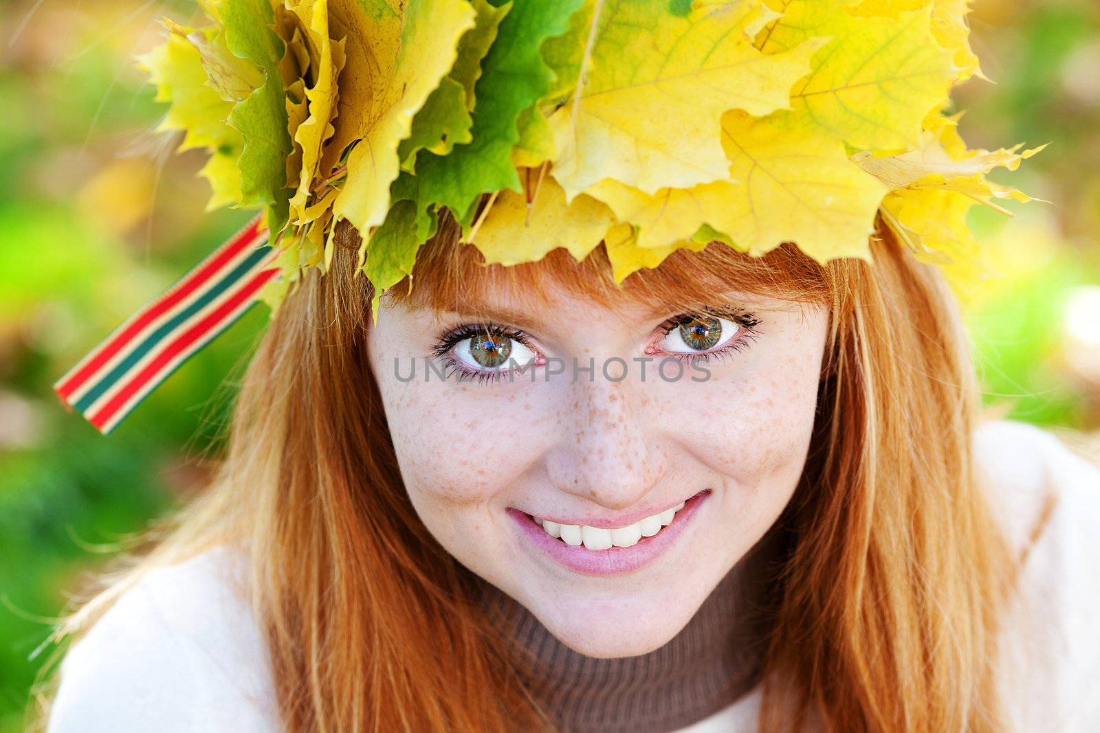portrait of a beautiful young redhead teenager woman in a wreath of maple leaves