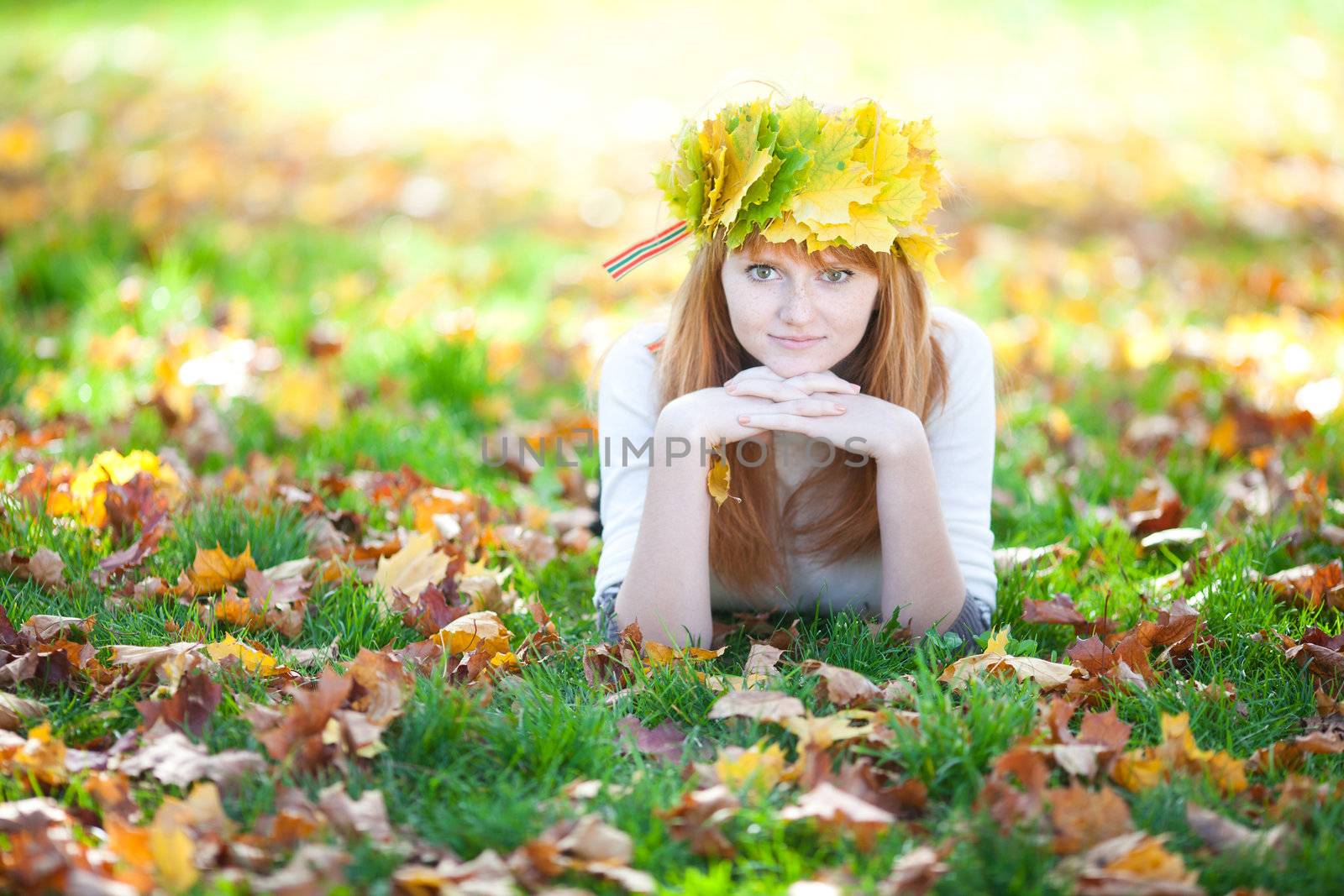 young redhead teenager woman in a wreath of maple leaves lying o by jannyjus