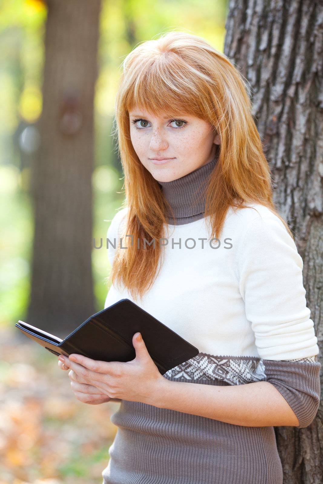 portrait of a beautiful young redhead teenager woman reading a book