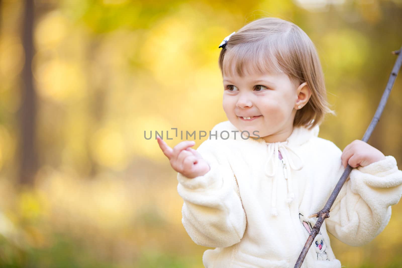 beautiful little girl with a stick on the autumn forest
