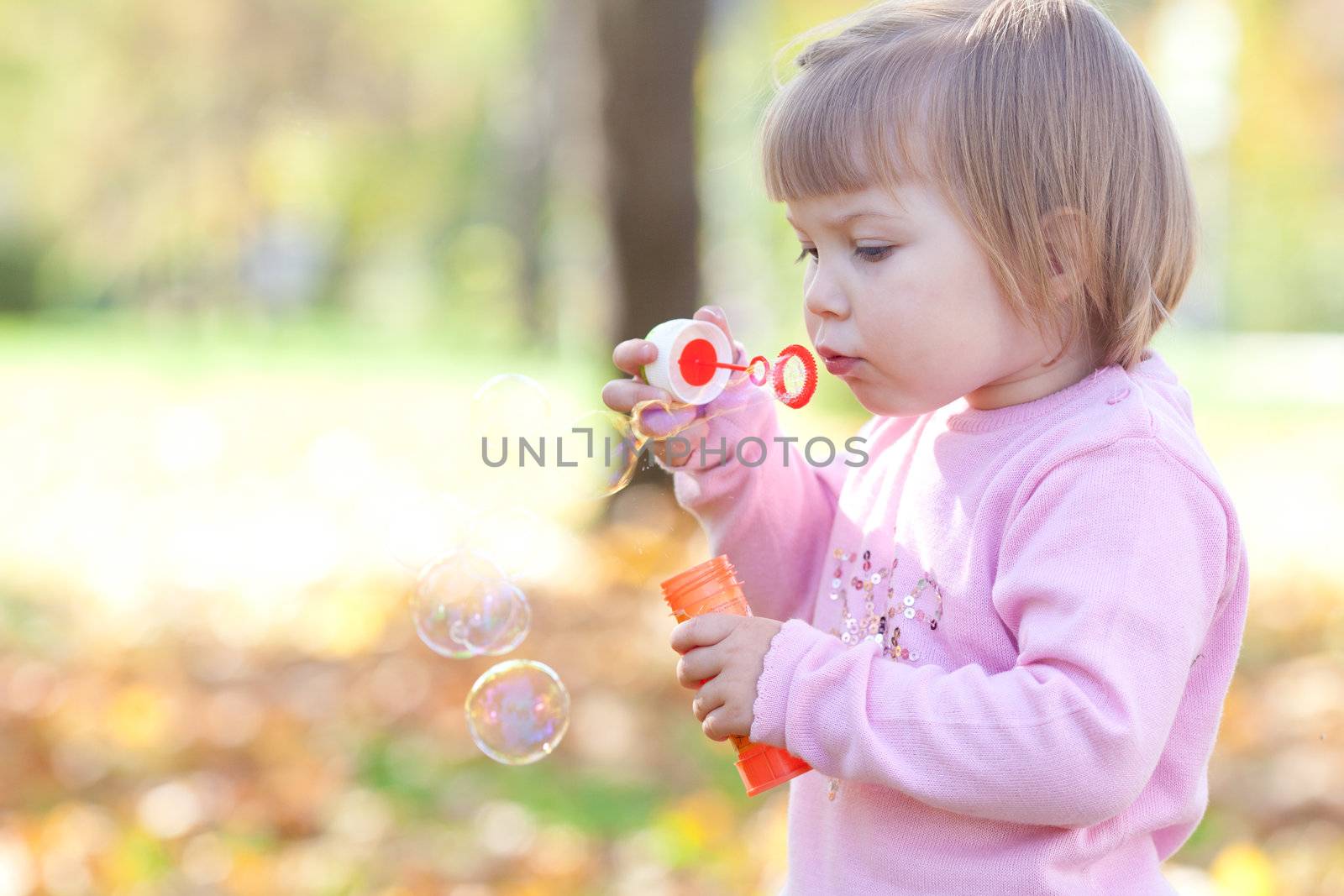 beautiful little girl making  bubble blower on the autumn forest