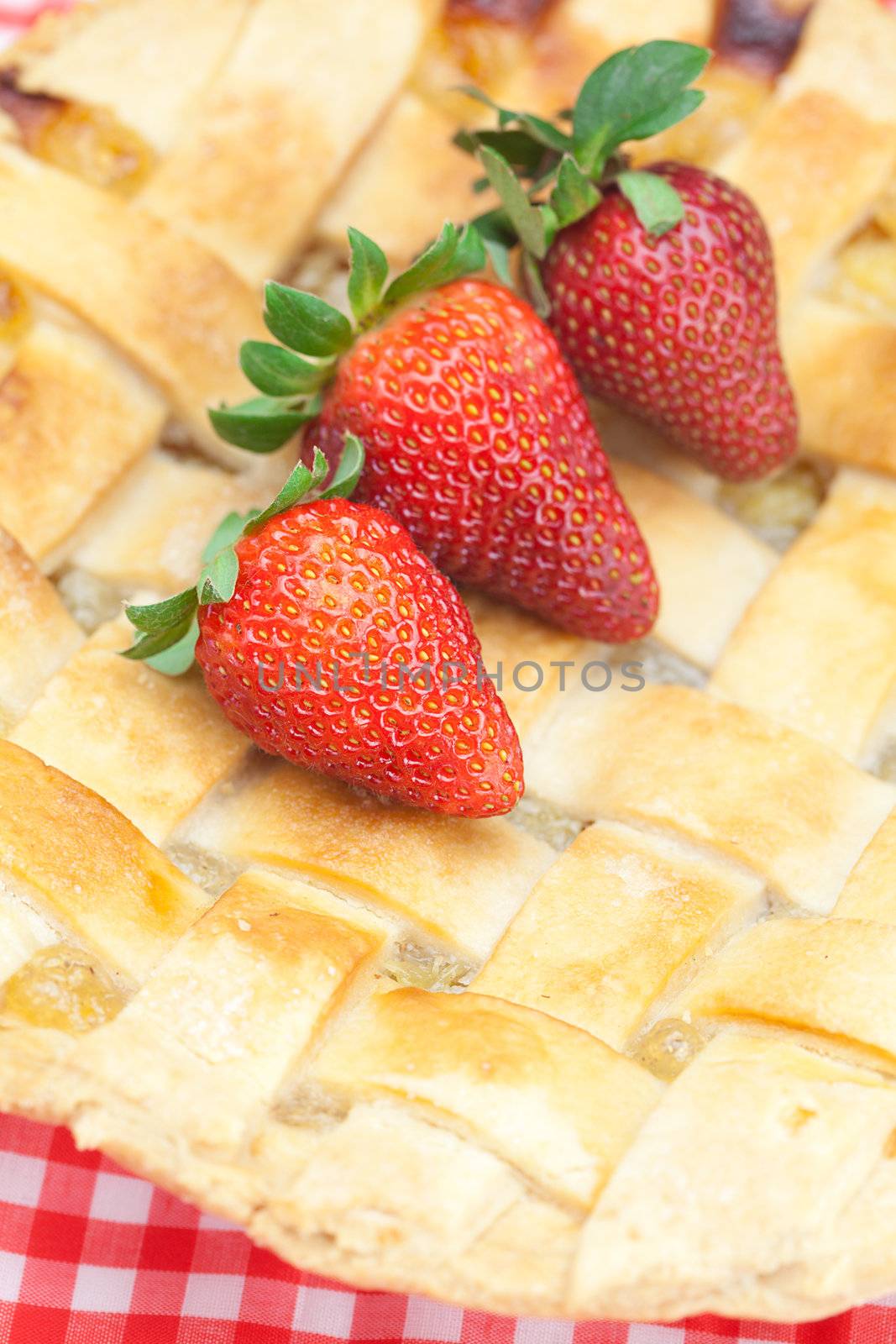 apple pie and a strawberry on plaid fabric