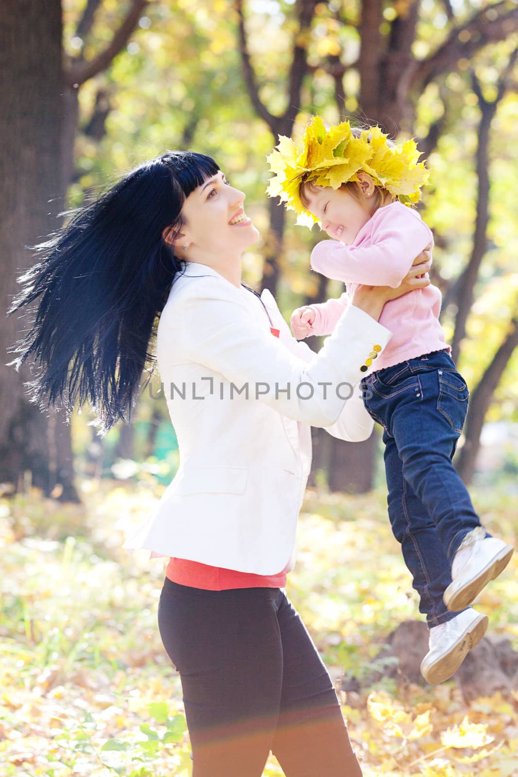 beautiful young mother holding her daughter in a wreath of maple by jannyjus