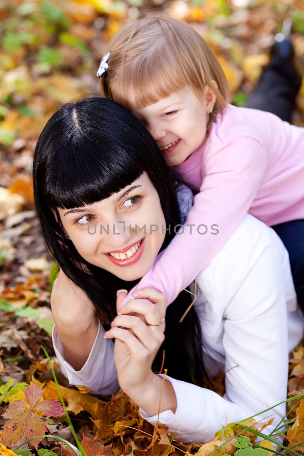 beautiful young mother and her daughter lying on the autumn leav by jannyjus