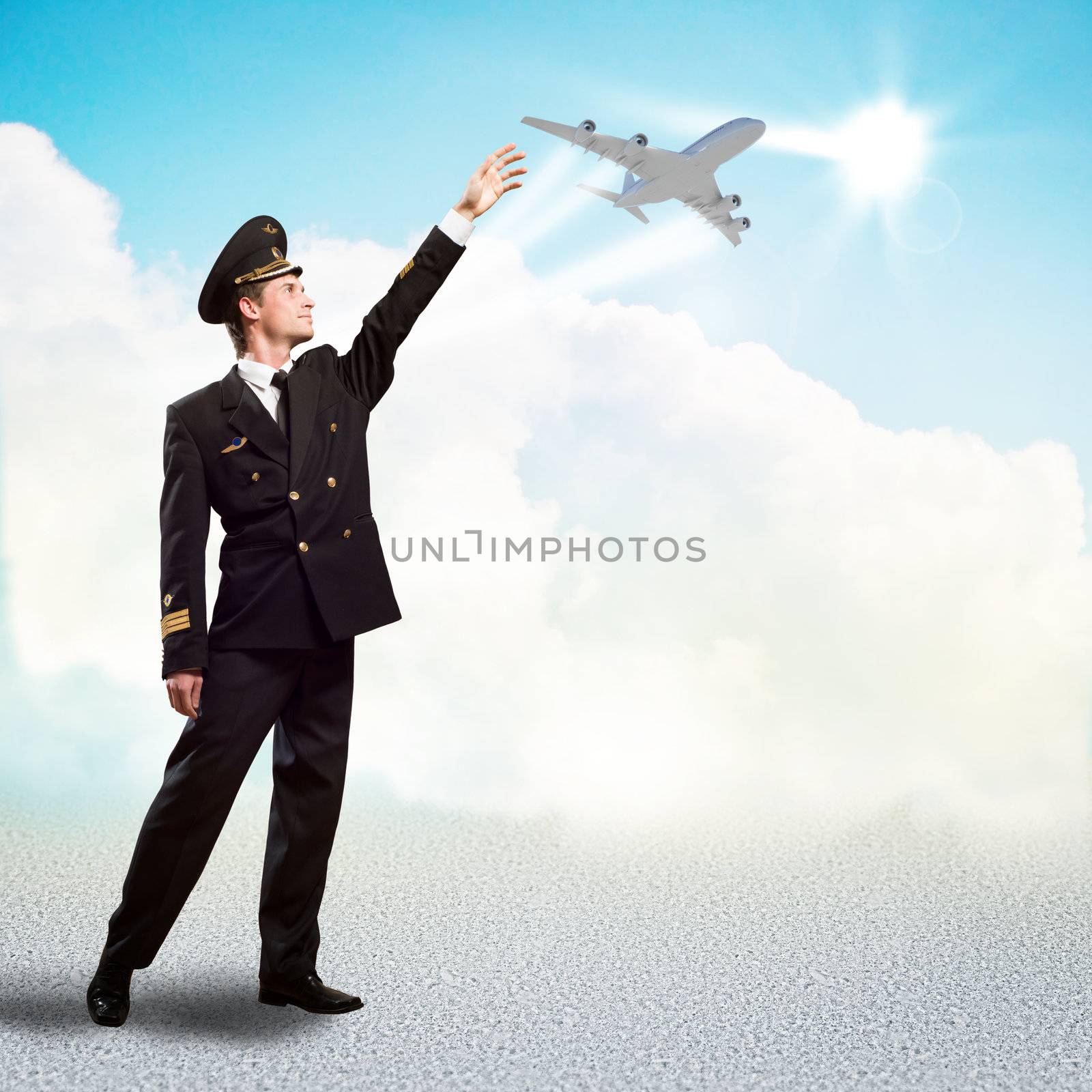 pilot in the form of extending a hand to a flying airplane on the background of clouds and sun