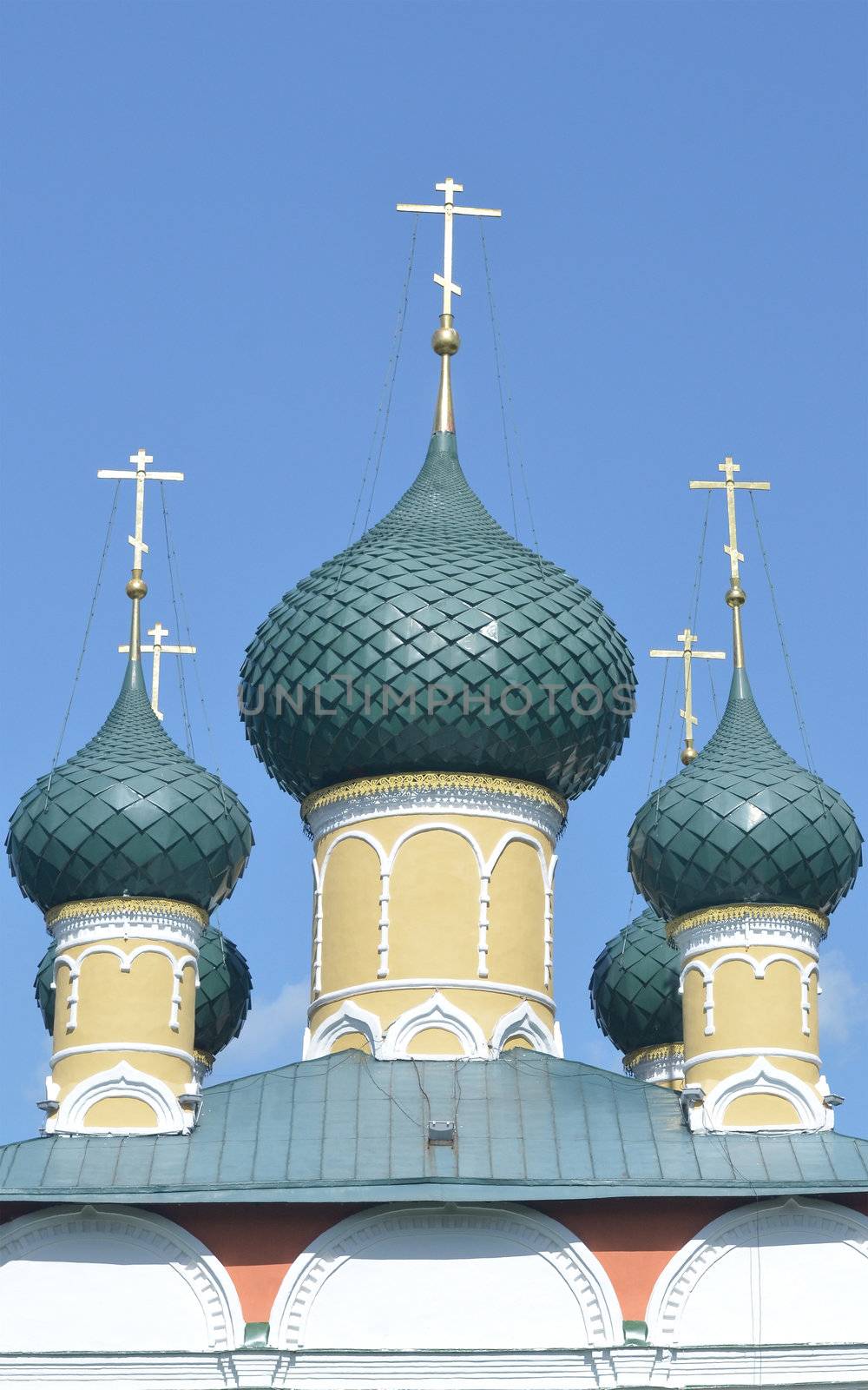 green domes of an Orthodox church with a gold cross on a background of the sky