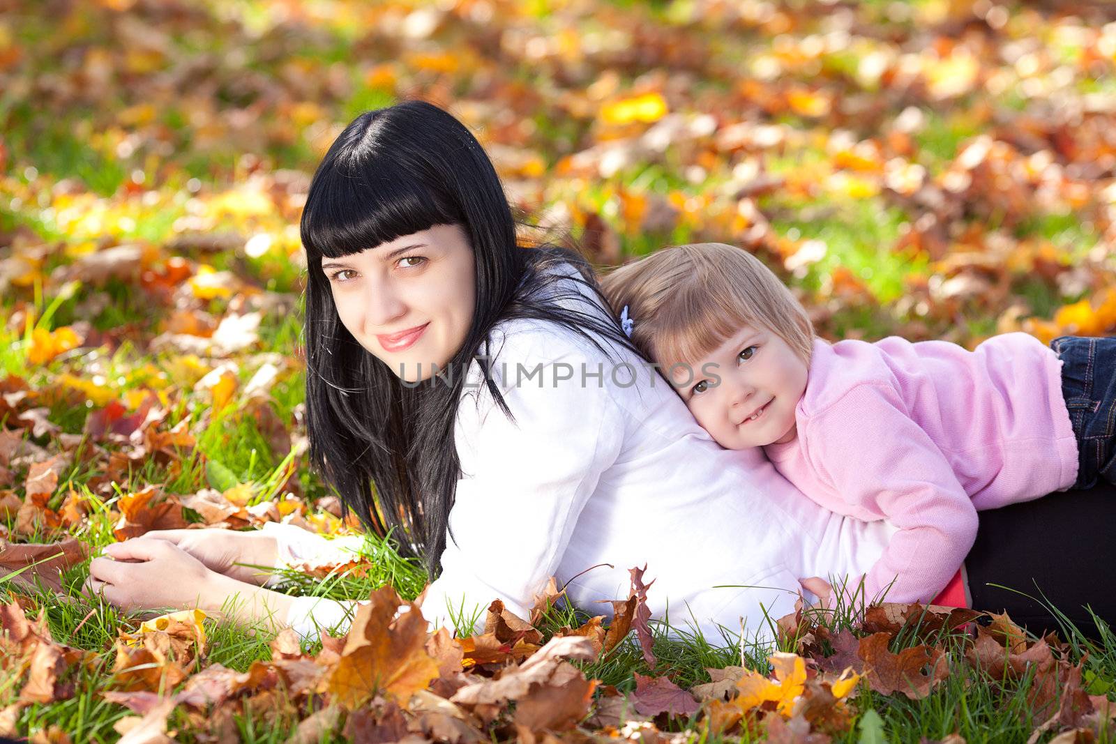 beautiful young mother and her daughter lying on the autumn leav by jannyjus