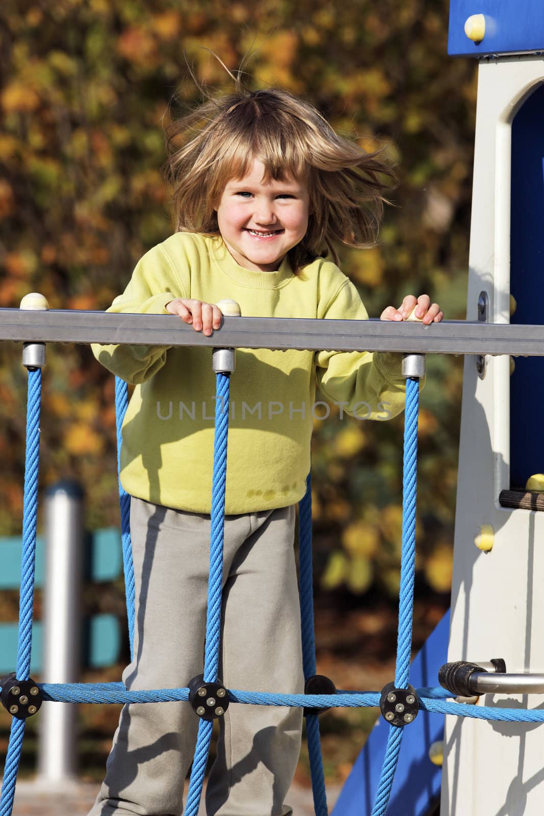 young child playing on colorful playground in autumn