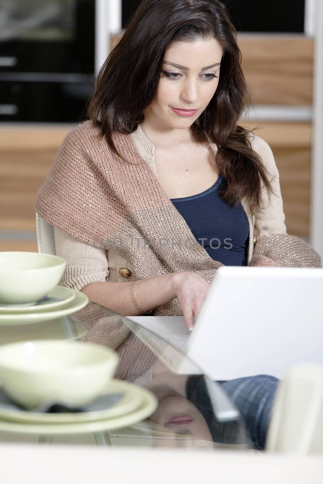 Attractive young woman using her laptop in the kitchen