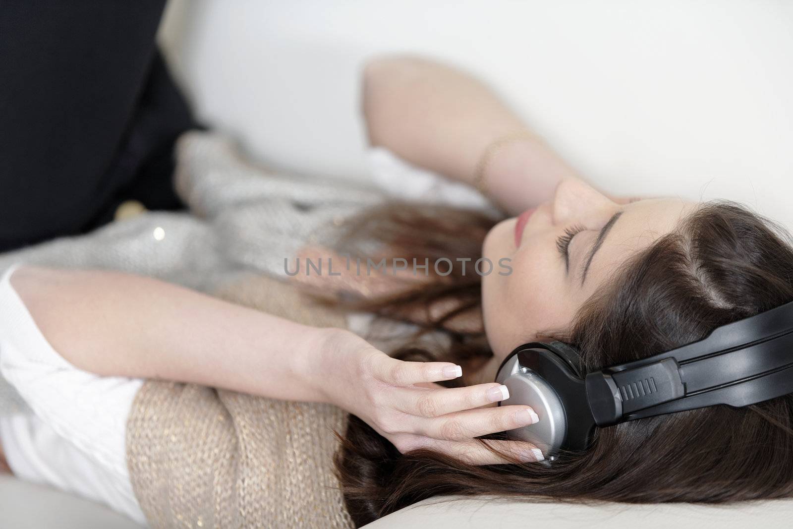 Attractive woman sat on a white sofa listening to music