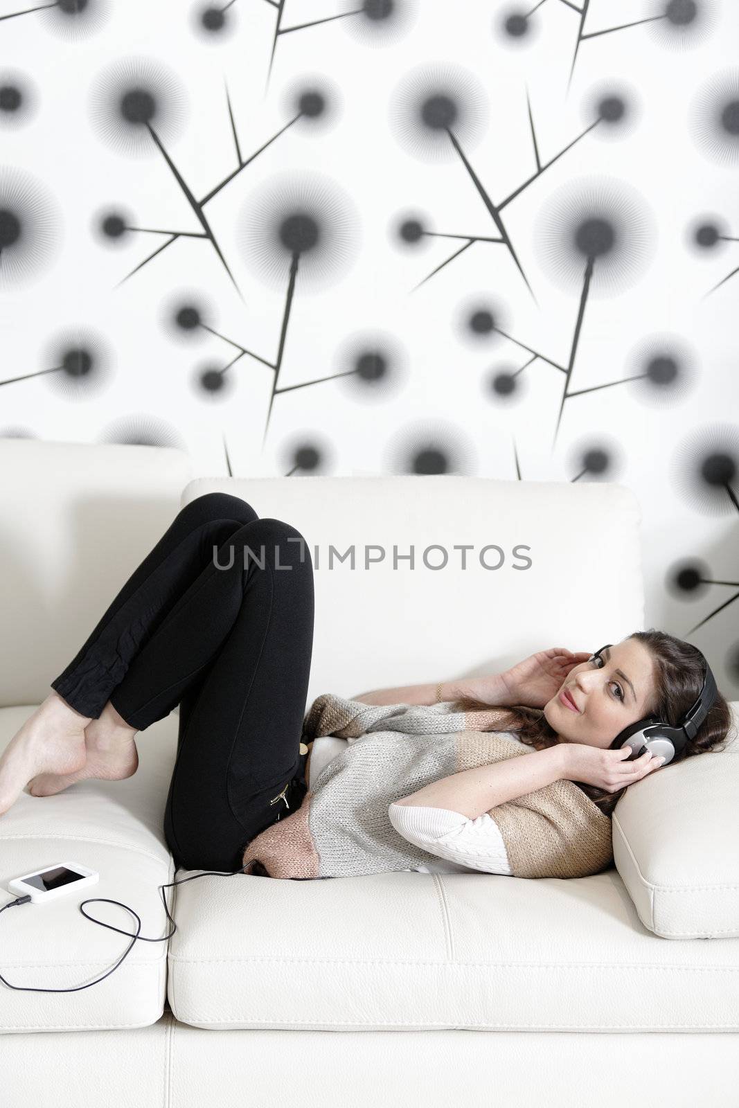 Attractive woman sat on a white sofa listening to music