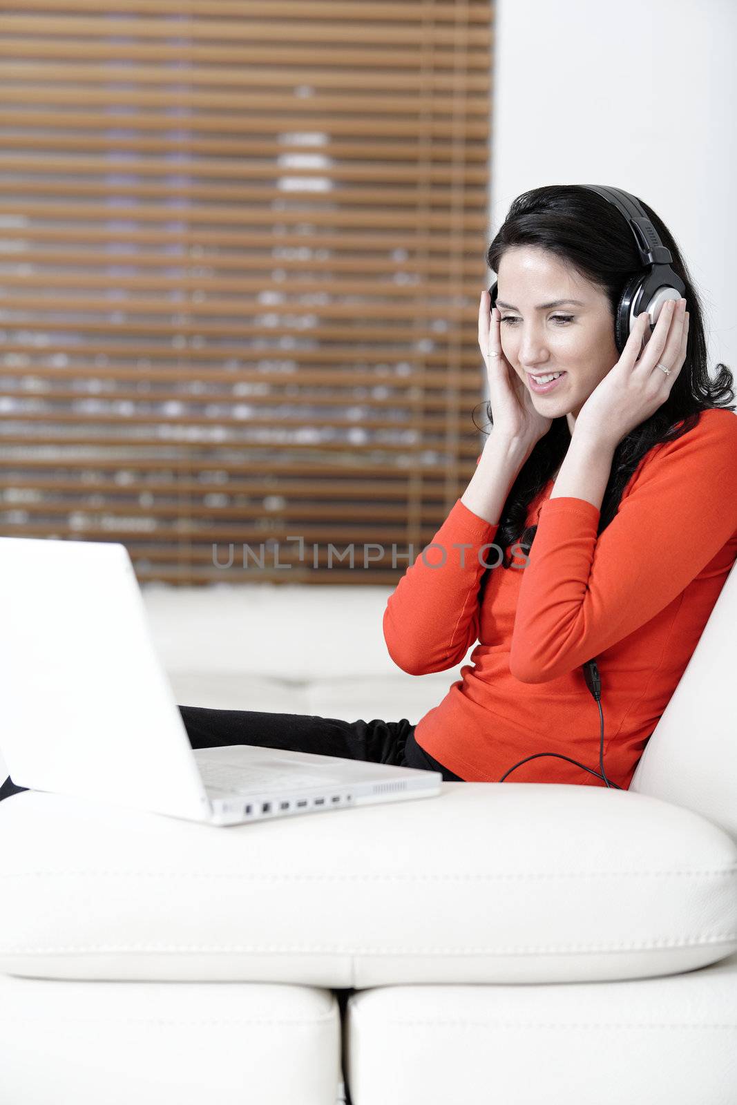 Attractive woman sat on a white sofa listening to music