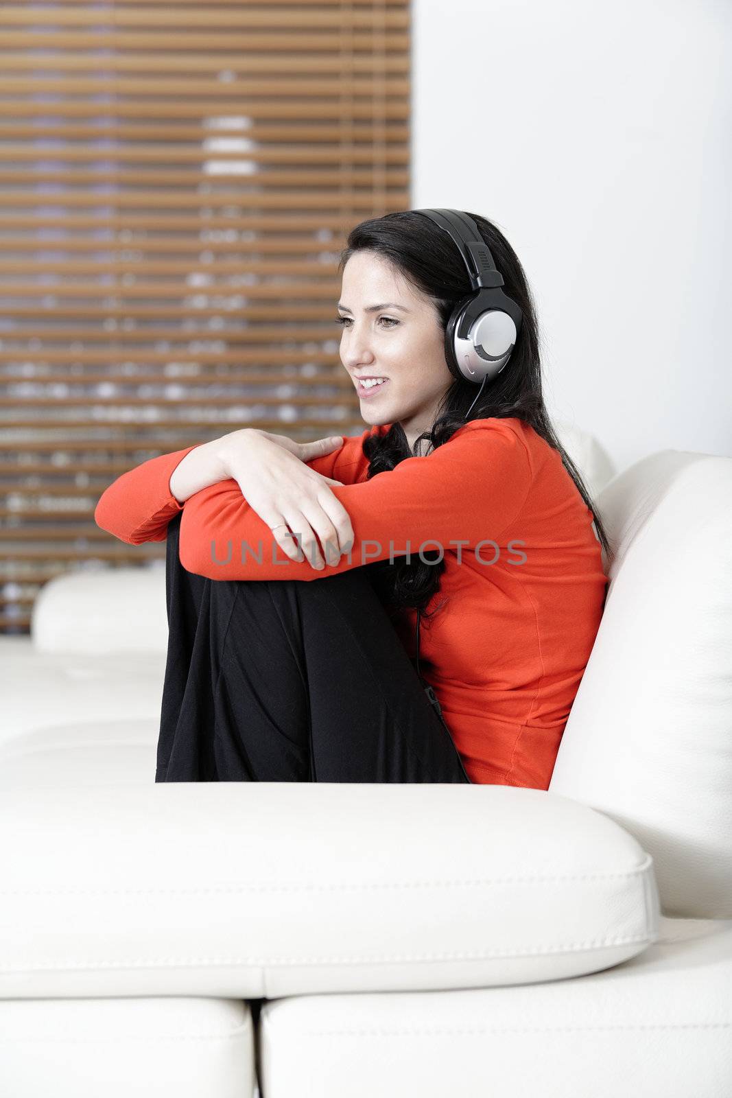 Attractive woman sat on a white sofa listening to music