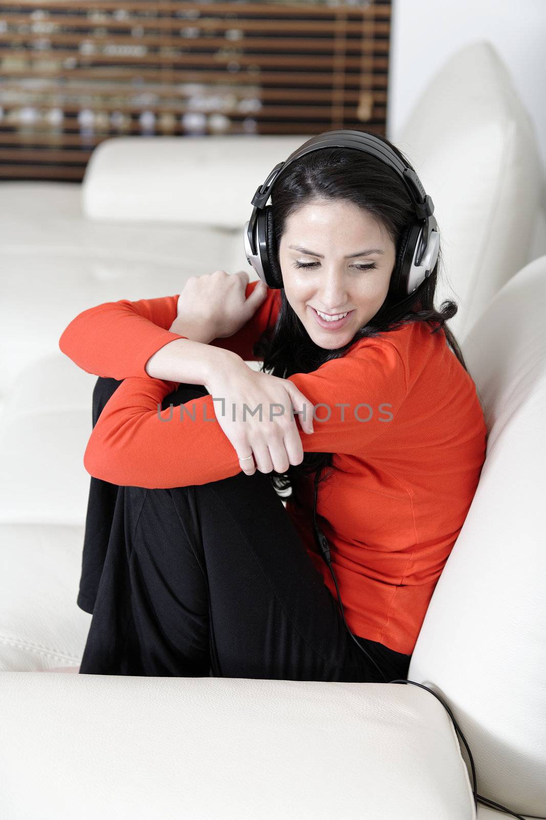 Attractive woman sat on a white sofa listening to music