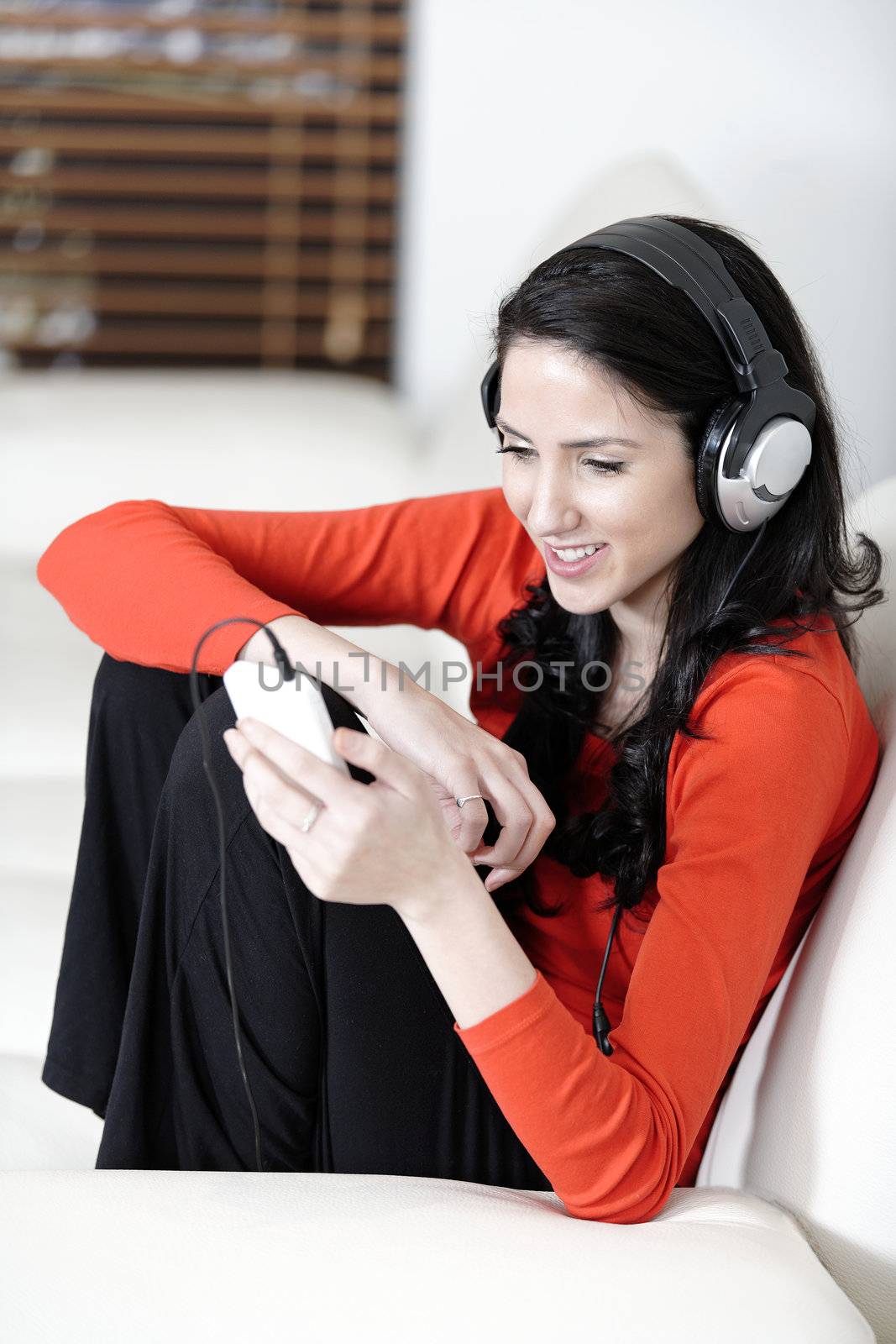 Attractive woman sat on a white sofa listening to music