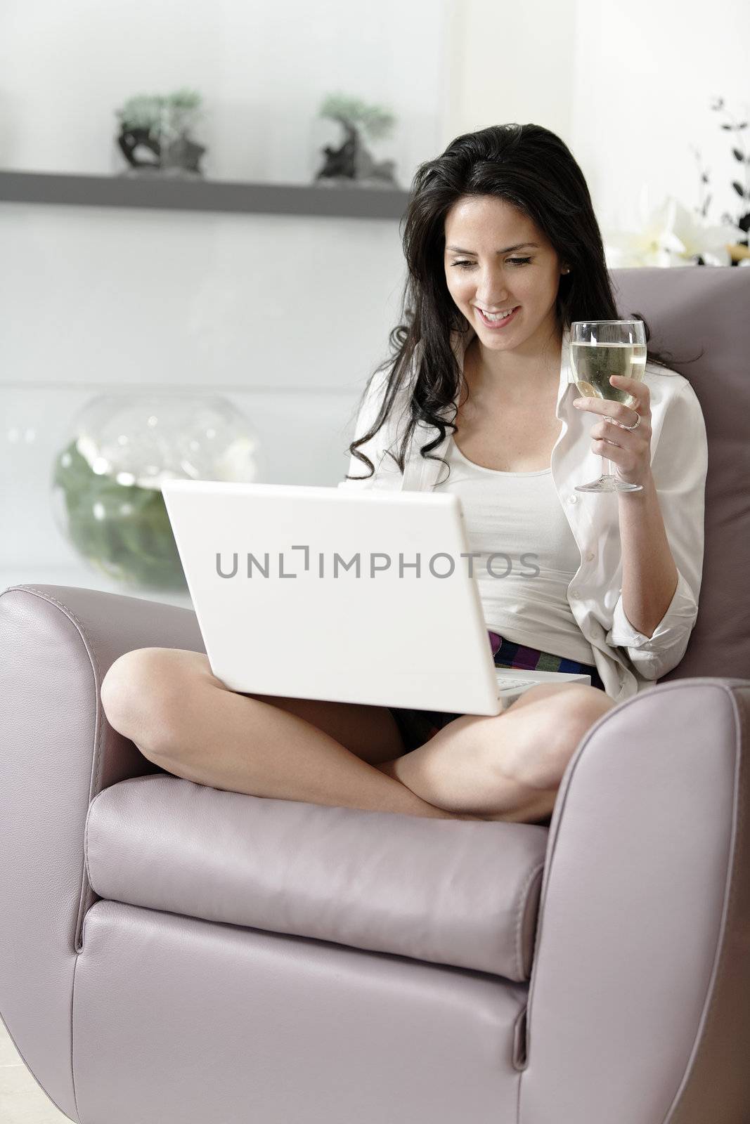 Beautiful young woman enjoying a glass of wine in her elegant living room.