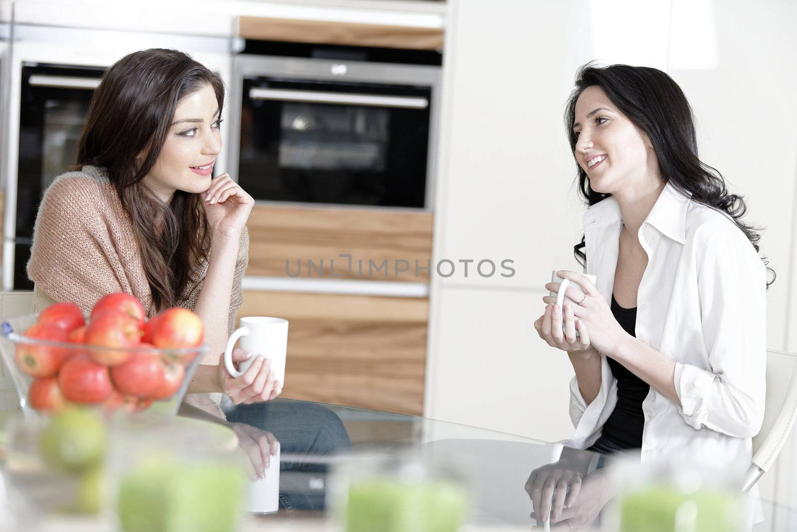 Two friends in a kitchen catching up and having fun.