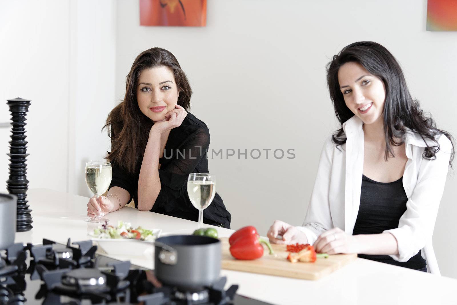Two friends in a kitchen cooking by studiofi