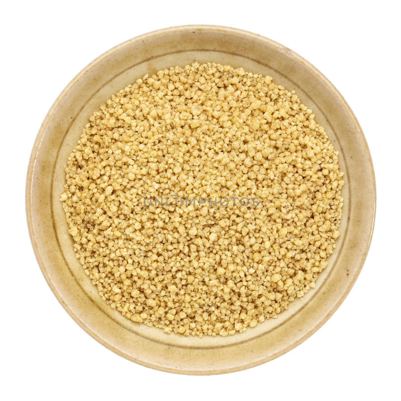 whole wheat couscous in a small ceramic bowl isolated on white, top view