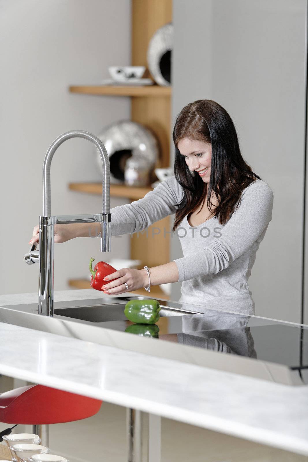 Beautiful young woman preparing food in her modern kitchen at home