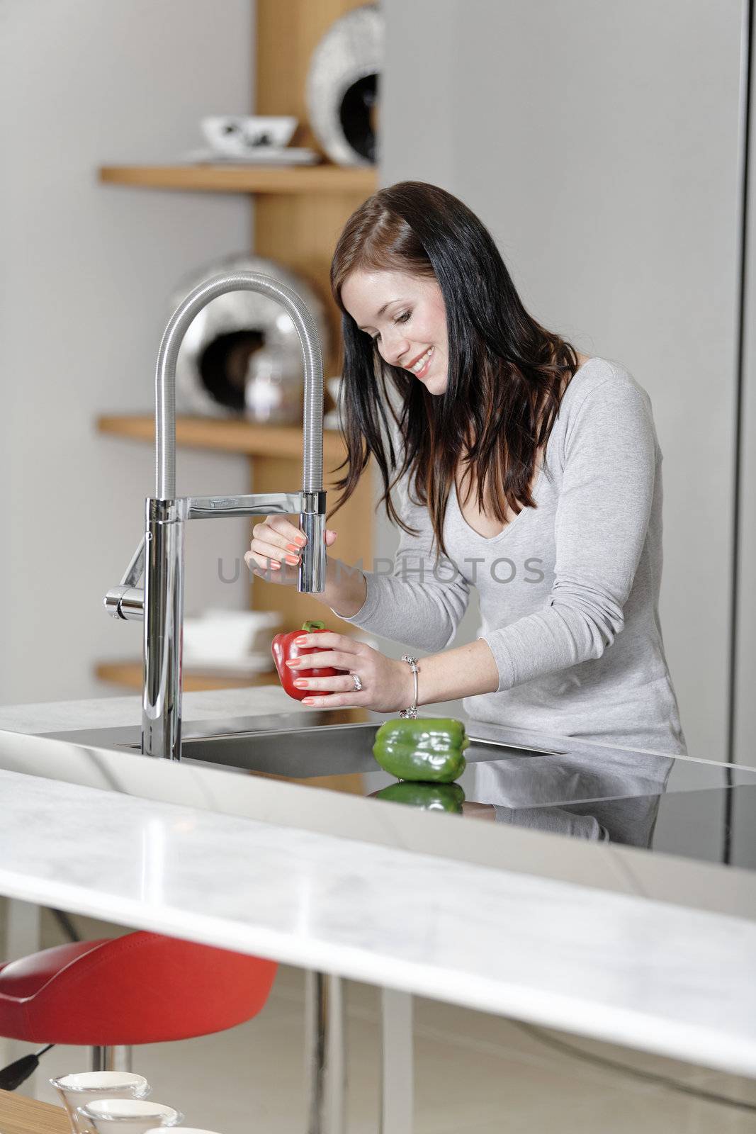 Woman rinsing peppers in a sink by studiofi