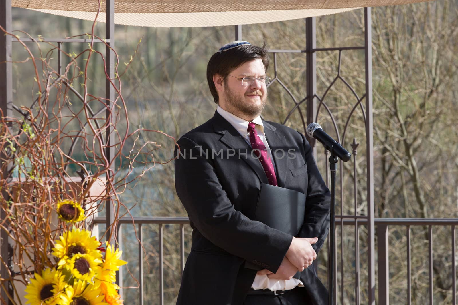 Smiling Caucasian Rabbi holding book by microphone