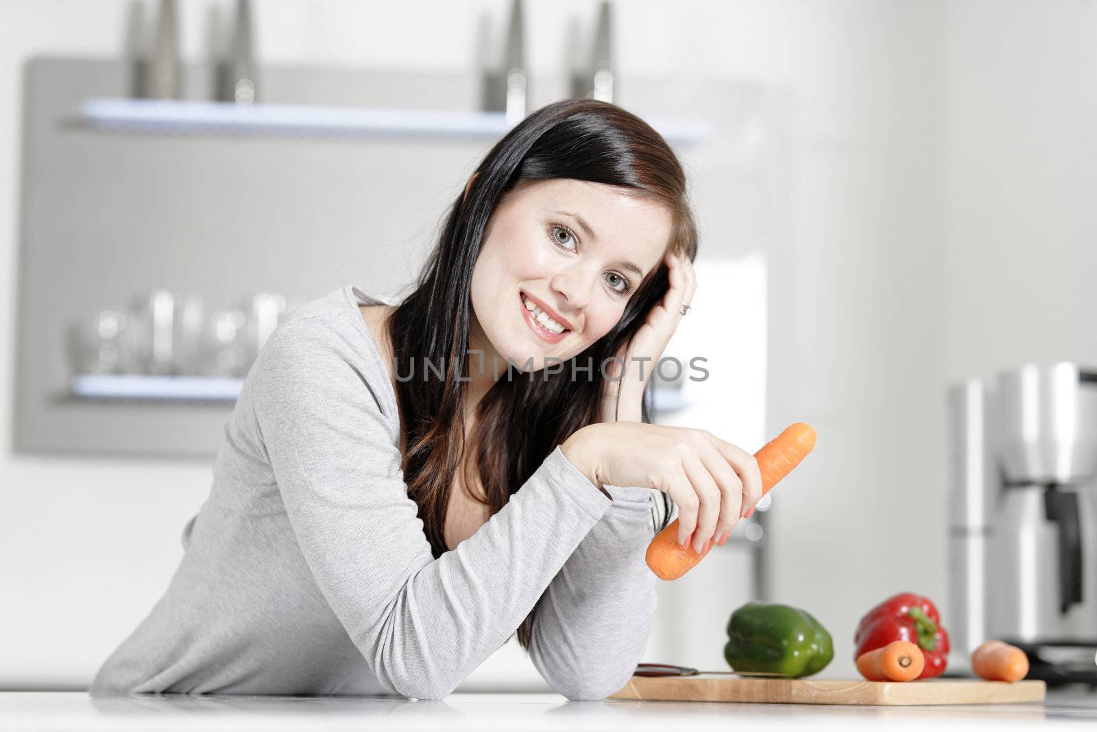 Attractive young woman in her elegant kitchen with fresh vegetables ready to cook.