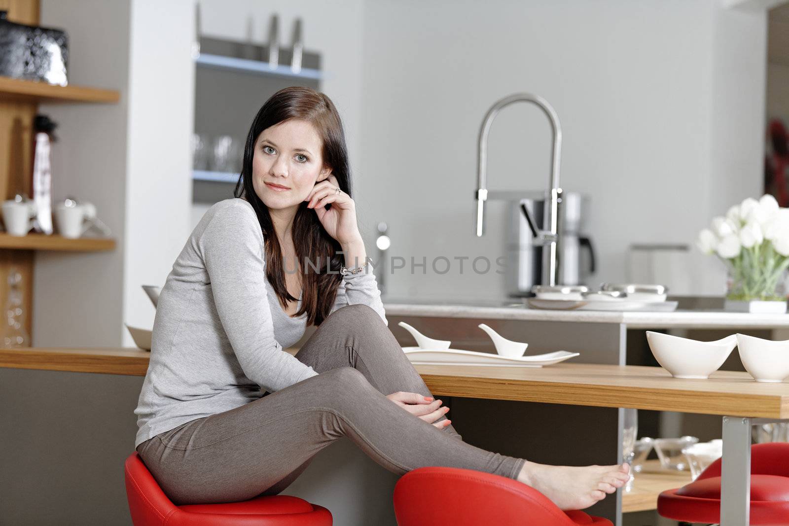 Attractive young woman taking a break in her kitchen with her feet up.