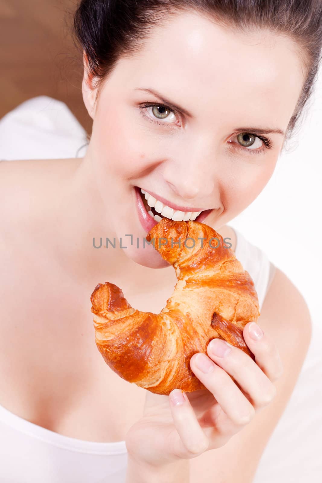 smiling woman portrait eating a croissant for breakfast 