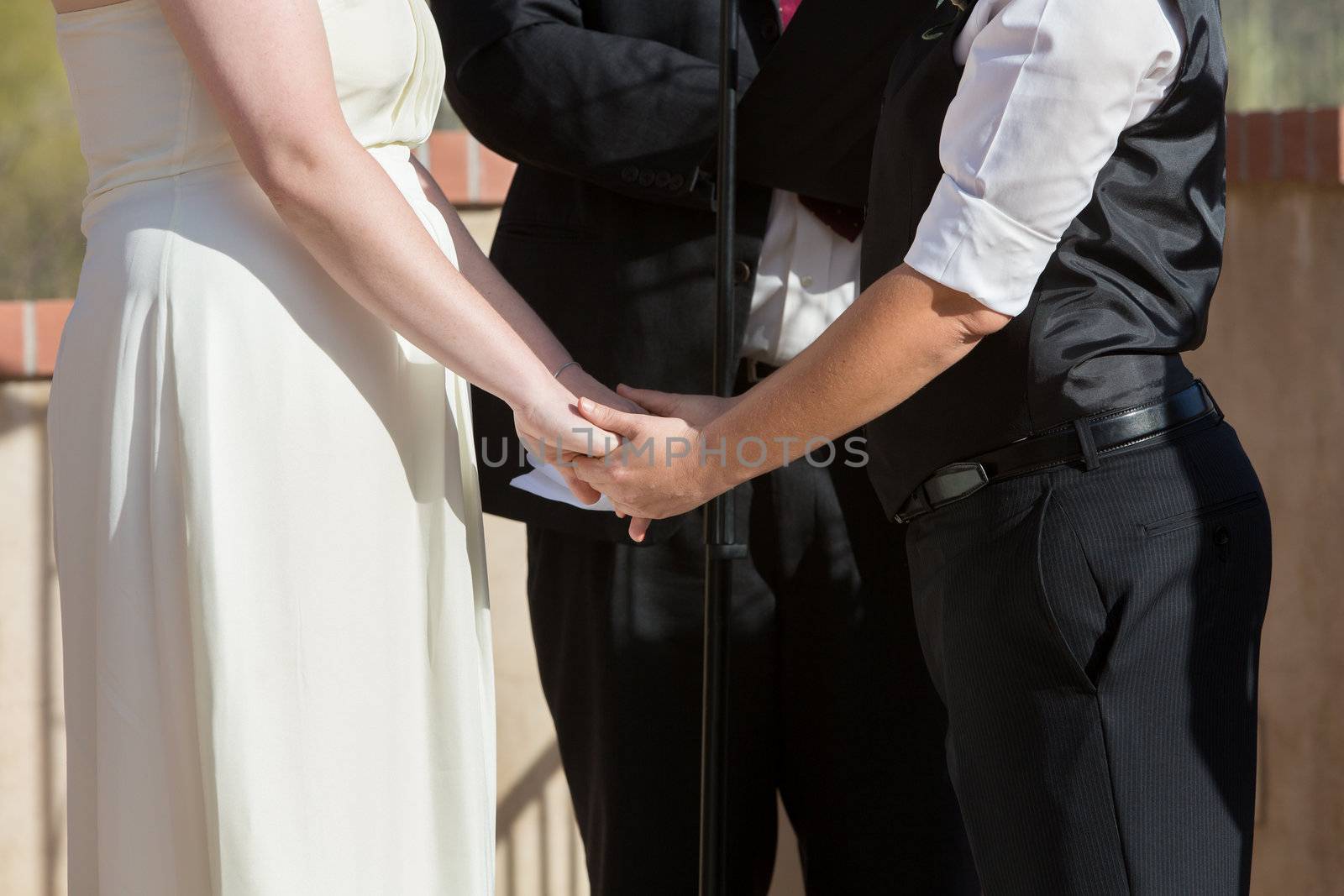 Women holding hands in wedding ceremony outdoors