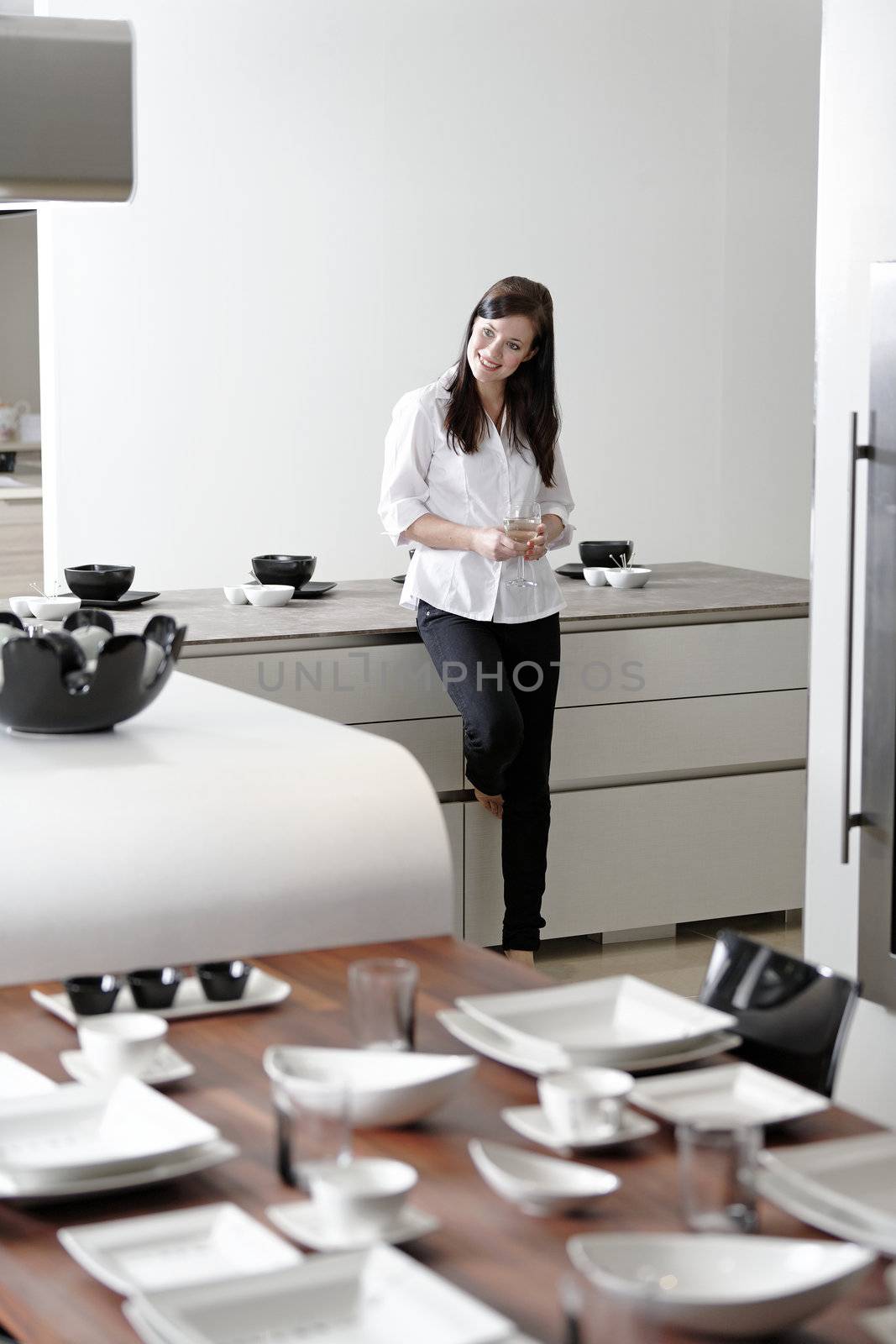 Beautiful young woman relaxing in her elegant white kitchen