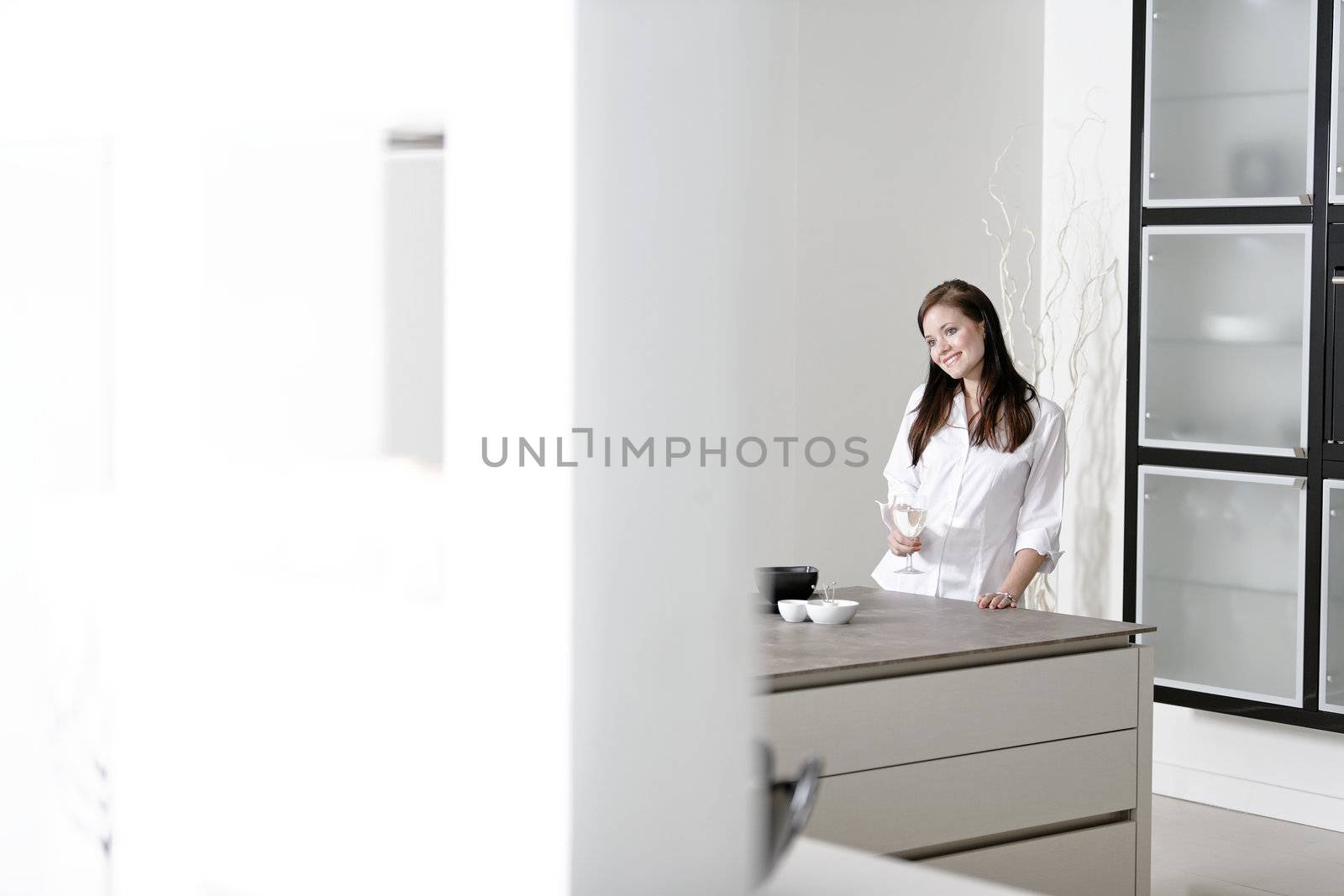 Beautiful young woman relaxing in her elegant white kitchen