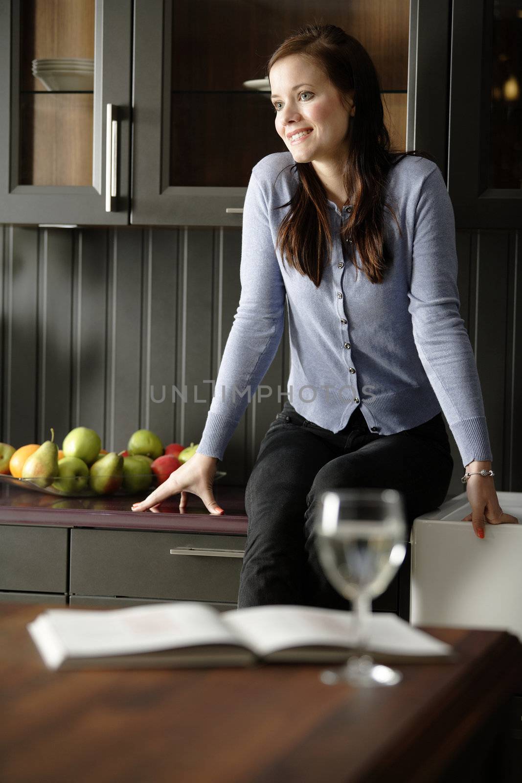 Attractive young woman enjoying a glass of wine in her kitchen.