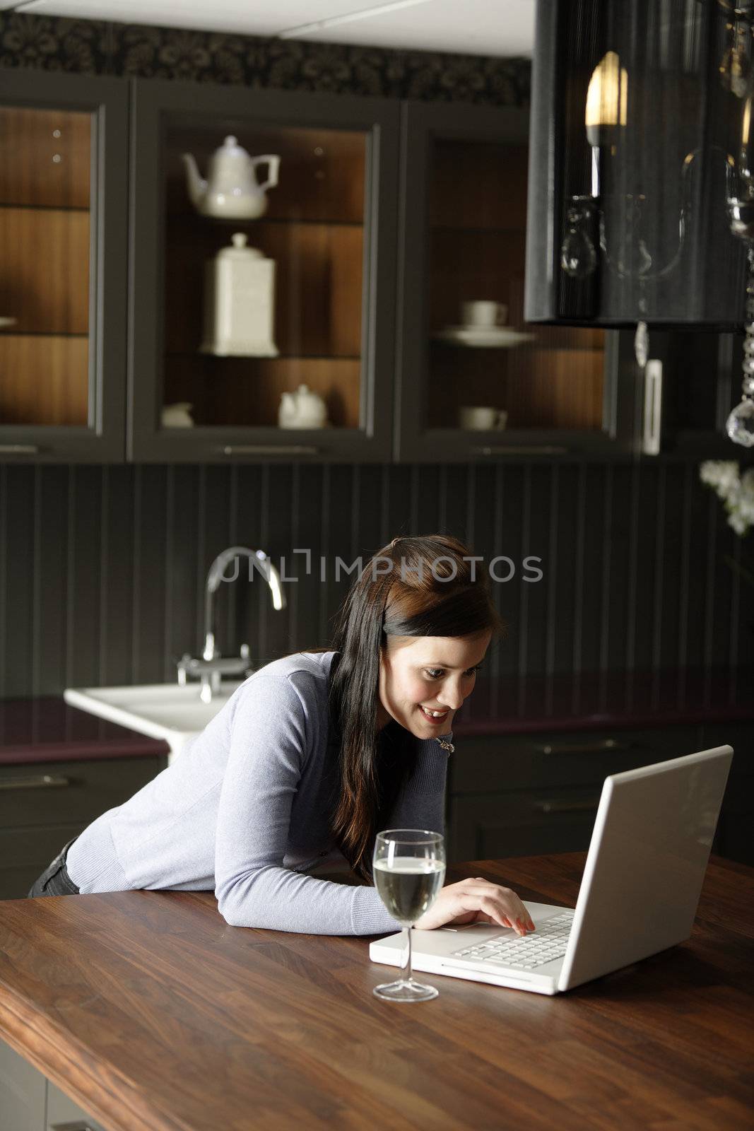 Attractive young woman using her laptop in the kitchen