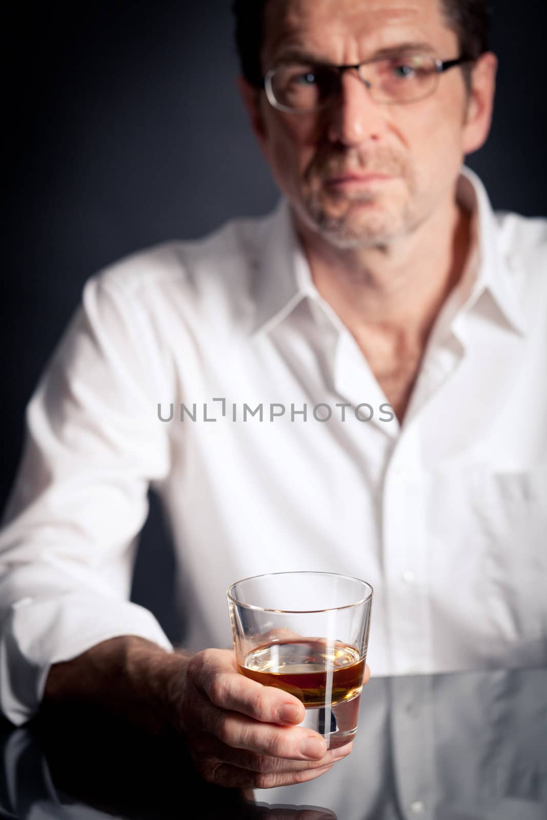 adult man holding an alcoholic drink thoughtful on black background